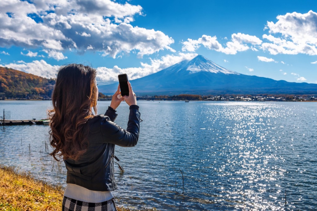 woman use mobile phone take photo fuji mountains kawaguchiko lake japan min